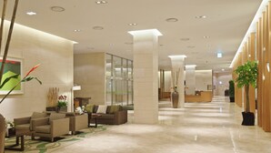 A spacious lobby with a reception desk, seating area, and decorative plants.
