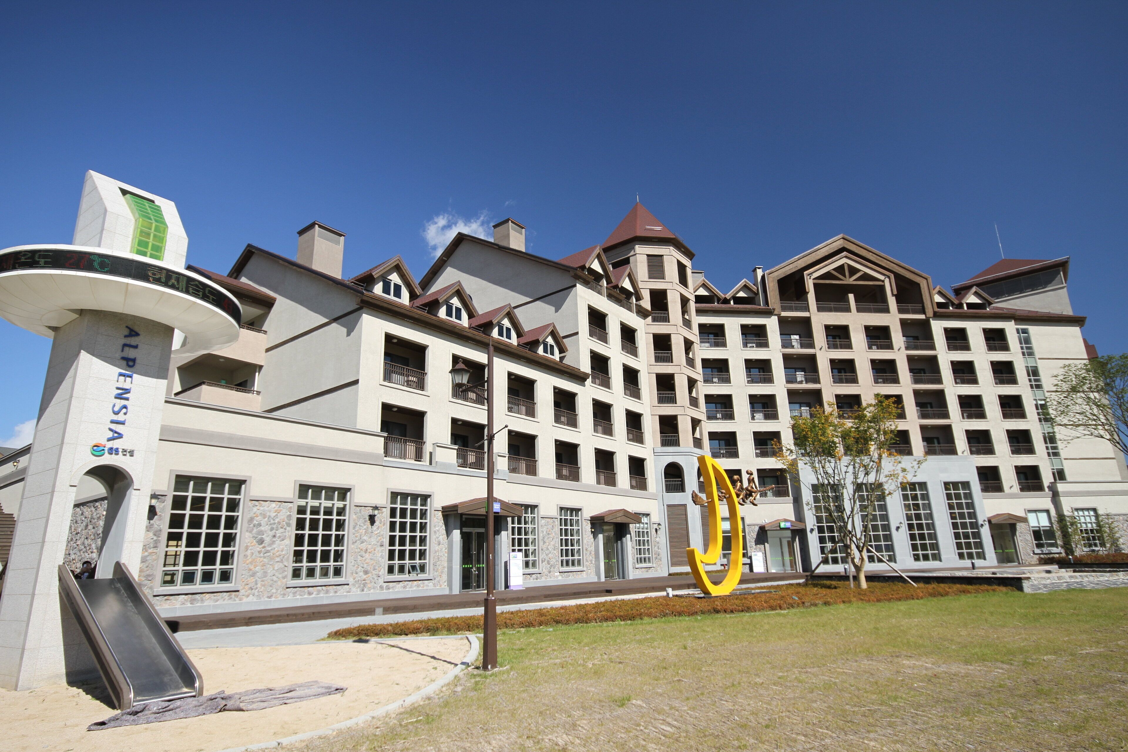 A multi-story hotel with a central atrium, balconies, and a prominent entrance with a sign.