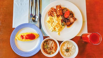 A table with plates of food, a glass of red drink, and a napkin with cutlery.