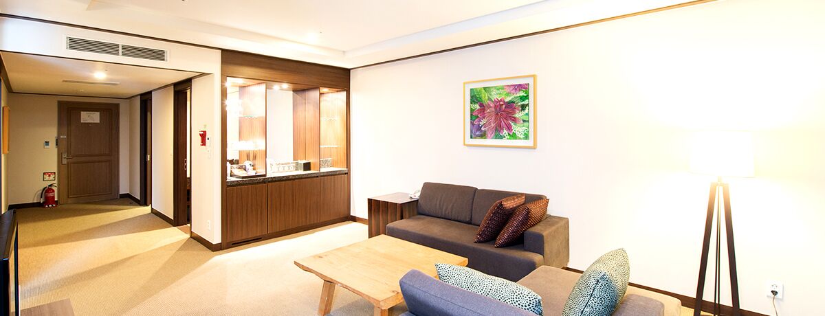 A modern living room with a sofa, a coffee table, and a kitchen area in the background.