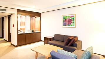 A modern living room with a sofa, a coffee table, and a kitchen area in the background.