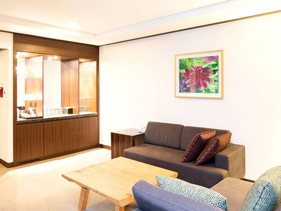 A modern living room with a sofa, a coffee table, and a kitchen area in the background.