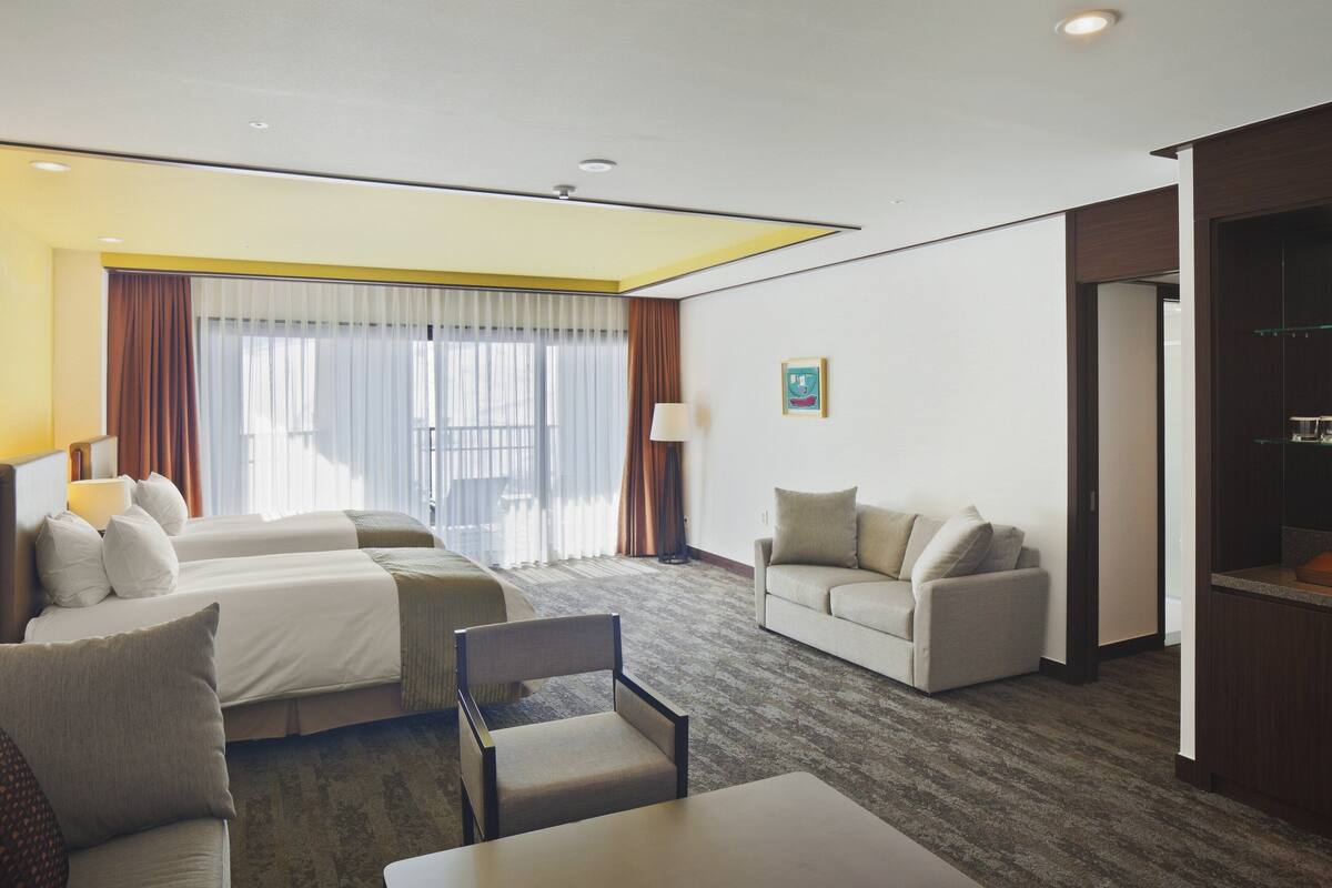 Une chambre d’hôtel avec deux lits, un canapé, une table à manger et un coin cuisine.