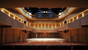 A large, modern auditorium with tiered seating and a central stage.