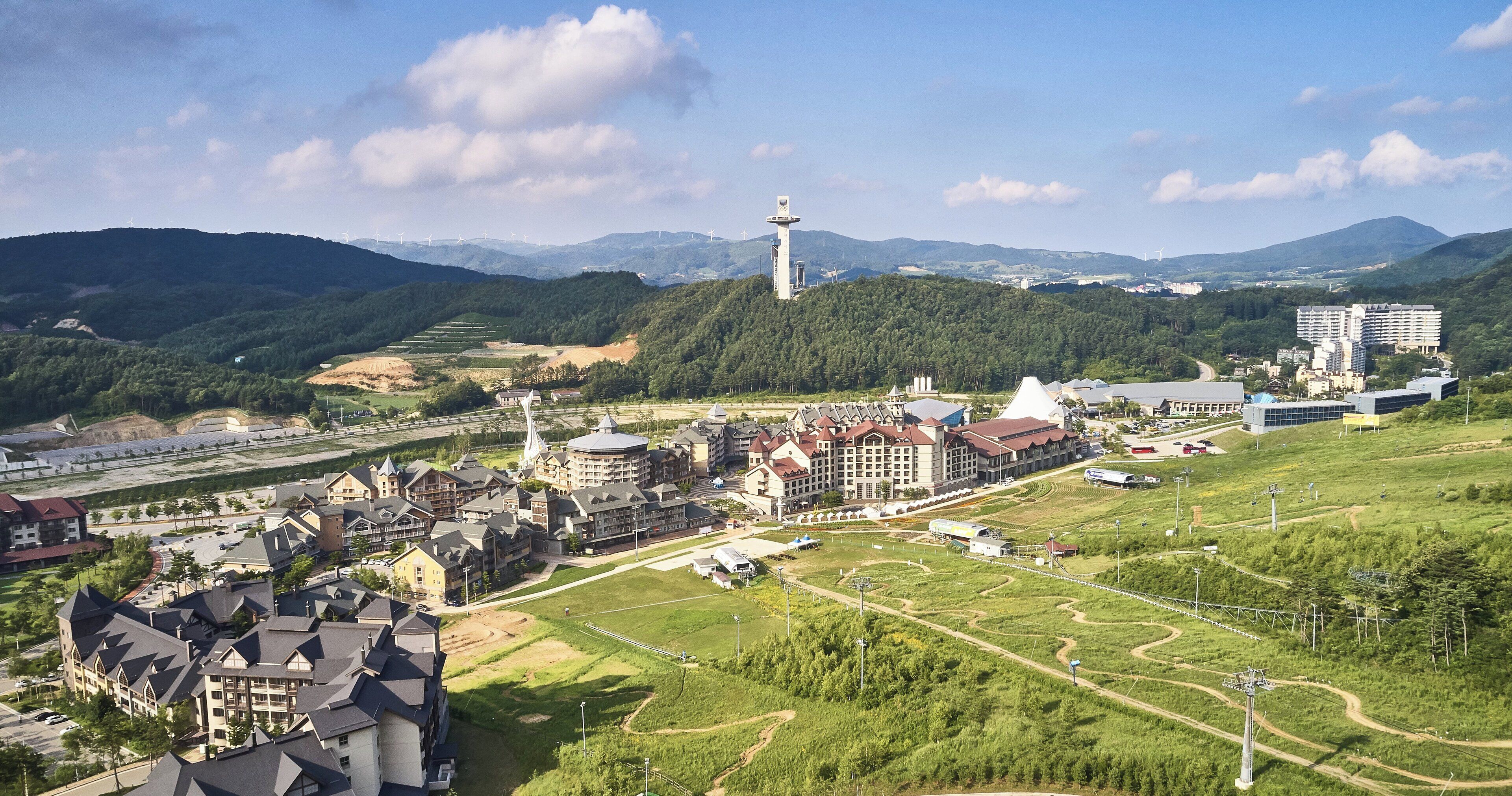 A hotel complex with multiple buildings, a central tower, and surrounding green areas.