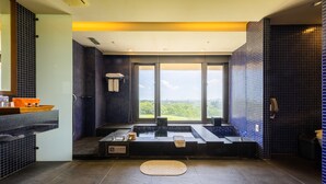 Un baño moderno con una bañera grande, un lavabo y una ventana que ofrece vistas al exterior.