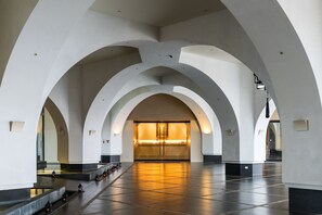 Tilava sisätila, jossa on keskeinen avoin alue, holvikatto ja heijastava lattia.