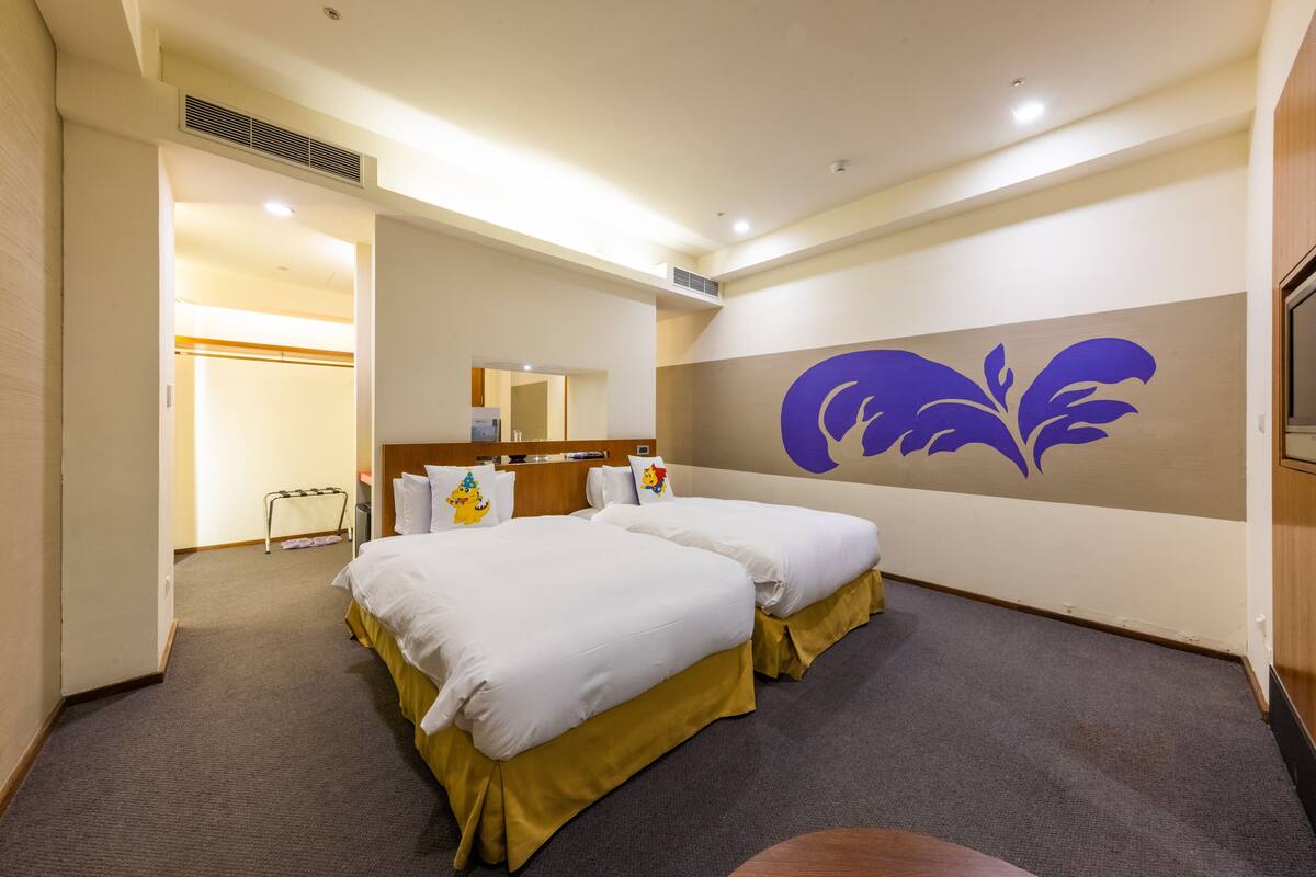 A hotel room with two beds, a large mirror, and a wall with a purple design.