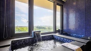 Enjoy a city view from the bathroom window, featuring a bathtub with a waterfall feature and a bench.