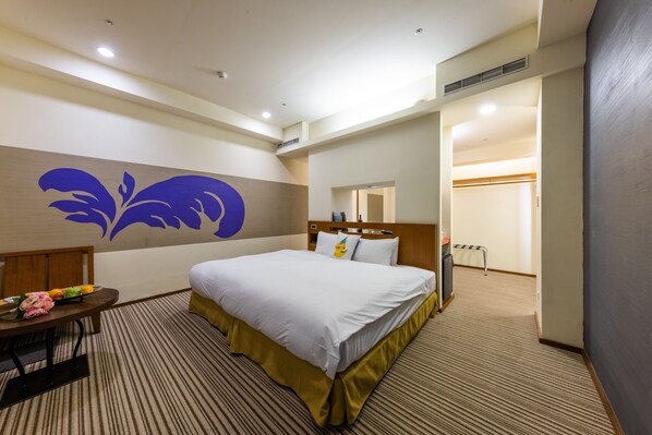Ein Hotelzimmer mit einem großen Bett, einem kleinen Tisch mit Blumenvase und einer Wand mit dekorativem Muster.