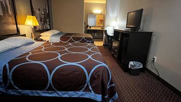 A hotel room with two beds, a desk, a television, and a bathroom in the background.