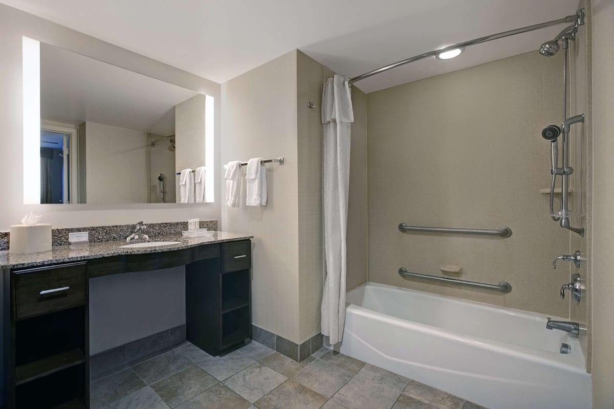 A modern bathroom with a bathtub, shower, and vanity.