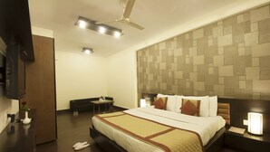 Habitación de hotel con una cama grande, un escritorio, una silla, un televisor y un ventilador de techo.