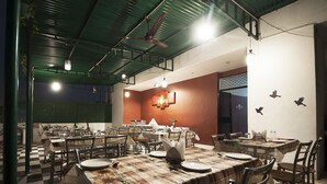 Un restaurante con varias mesas y sillas, piso a cuadros y techo verde.