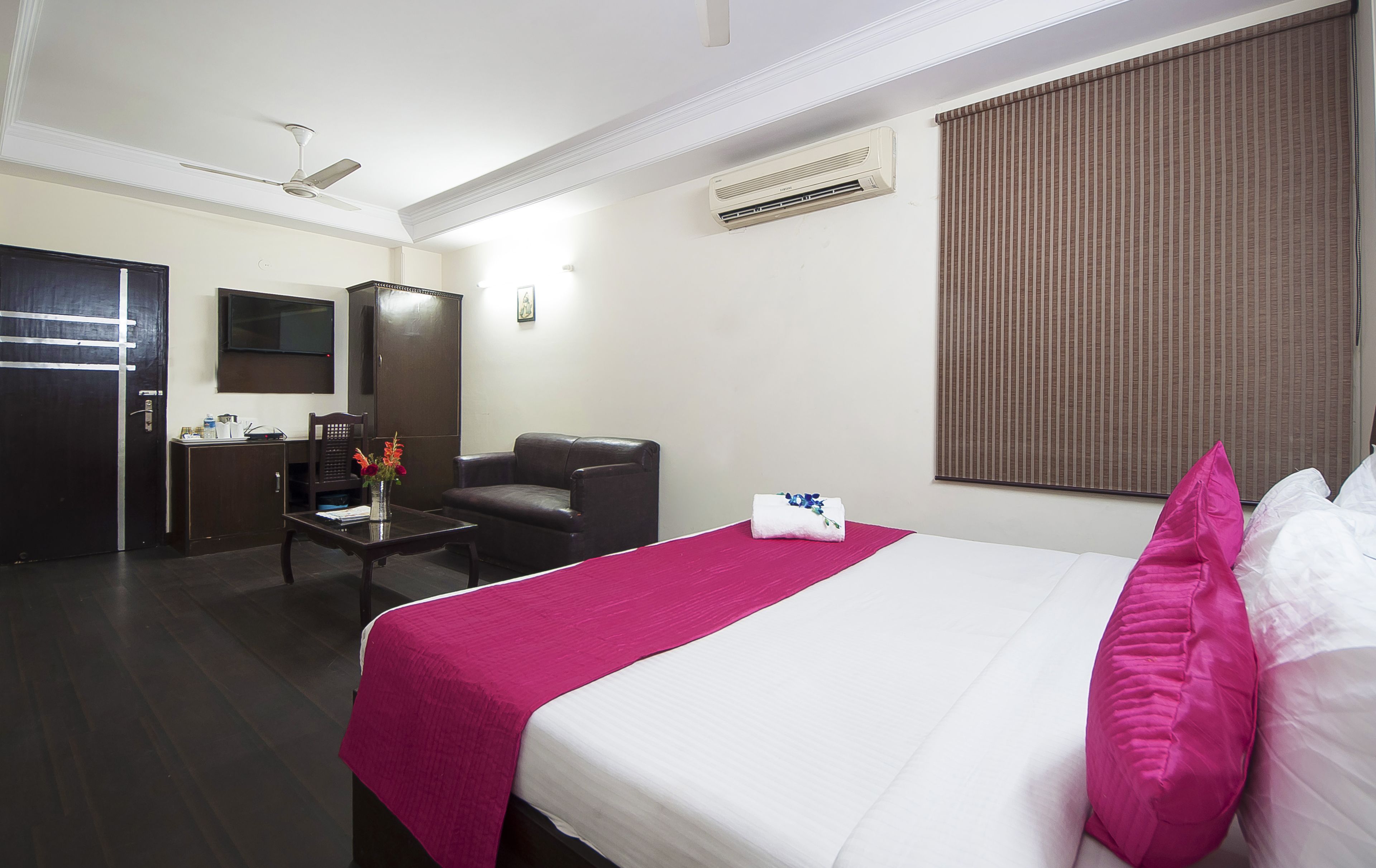 A hotel room with a bed, a desk, a chair, and a television.