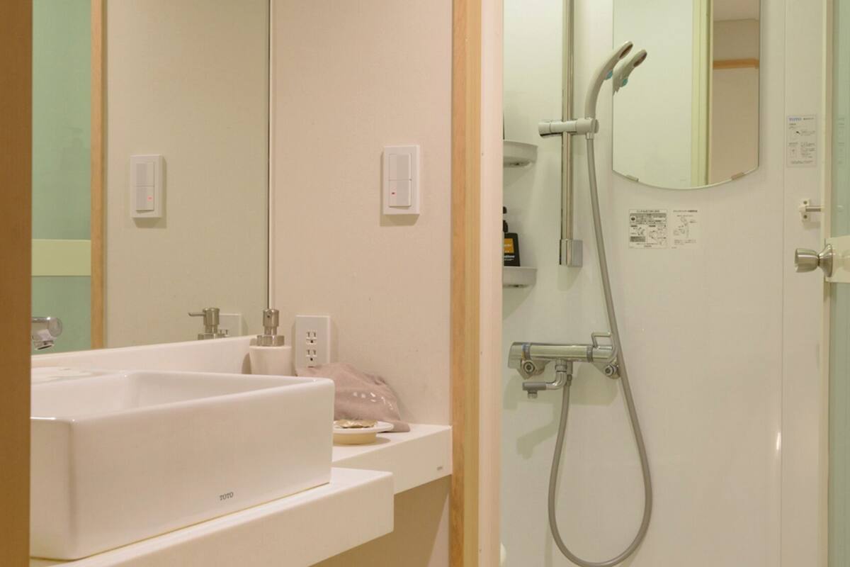 Een badkamer met een wit wastafelmeubel, spiegel en douche.