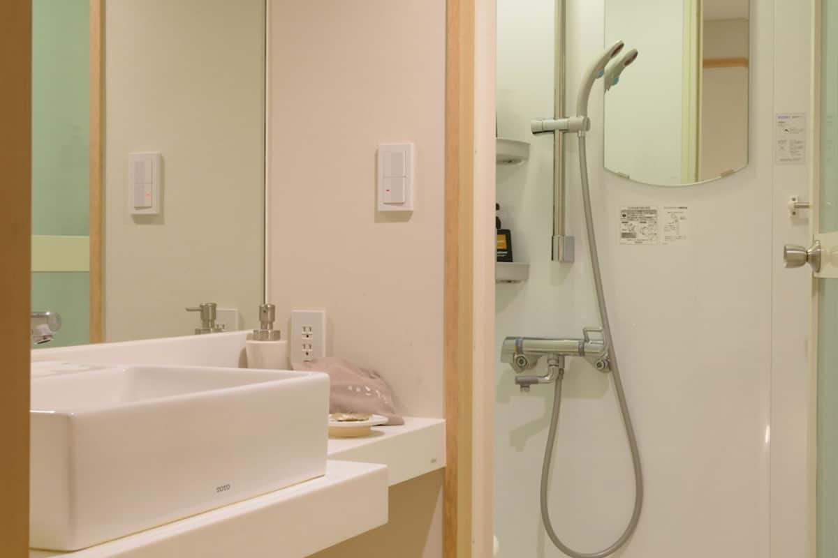 A bathroom with a white sink, mirror, and shower.
