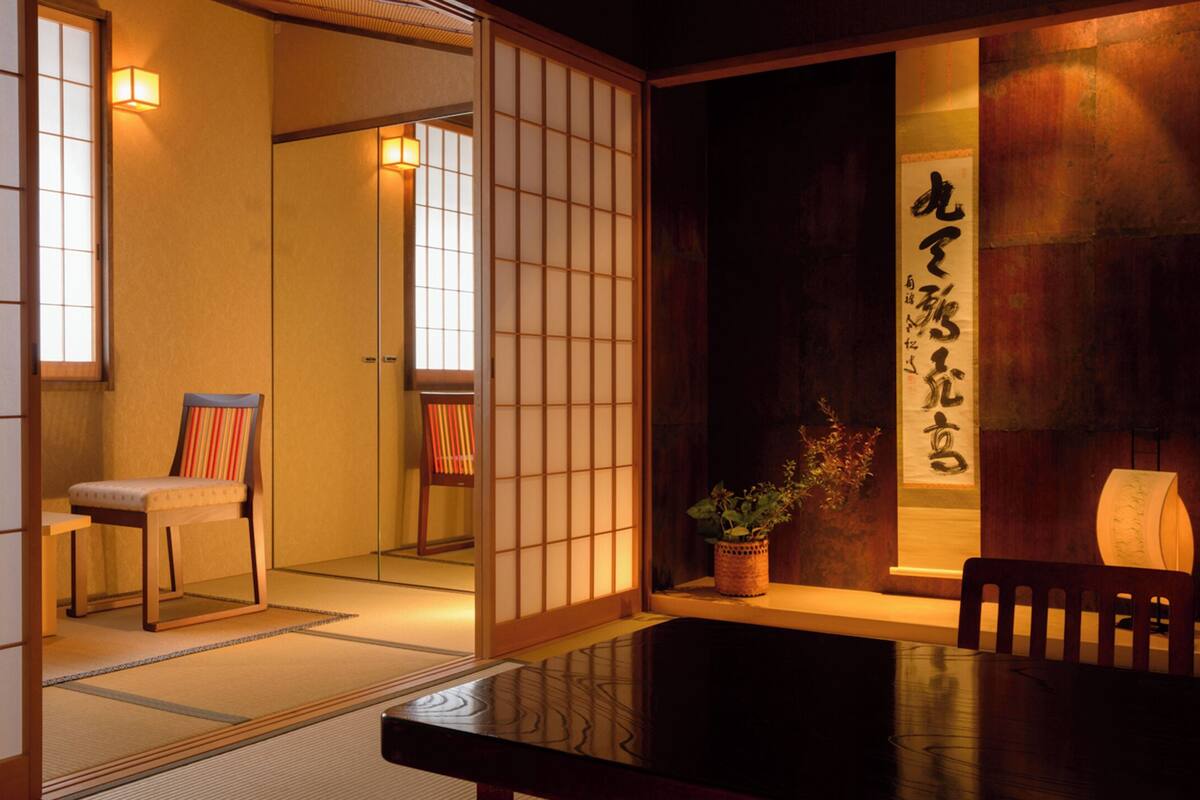Een traditionele Japanse kamer met tatami vloerbedekking, een lage tafel en een schuifdeur met kalligrafie.