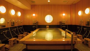 Una sauna con varias bancas e individuales cabinas de ducha, cada una con un espejo y una lámpara arriba.