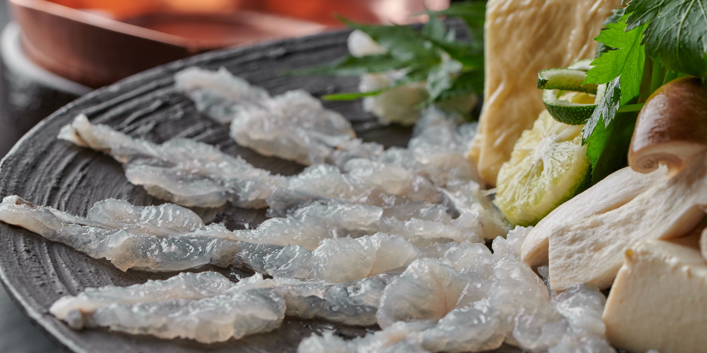 A plate with raw fish, lime, and herbs.
