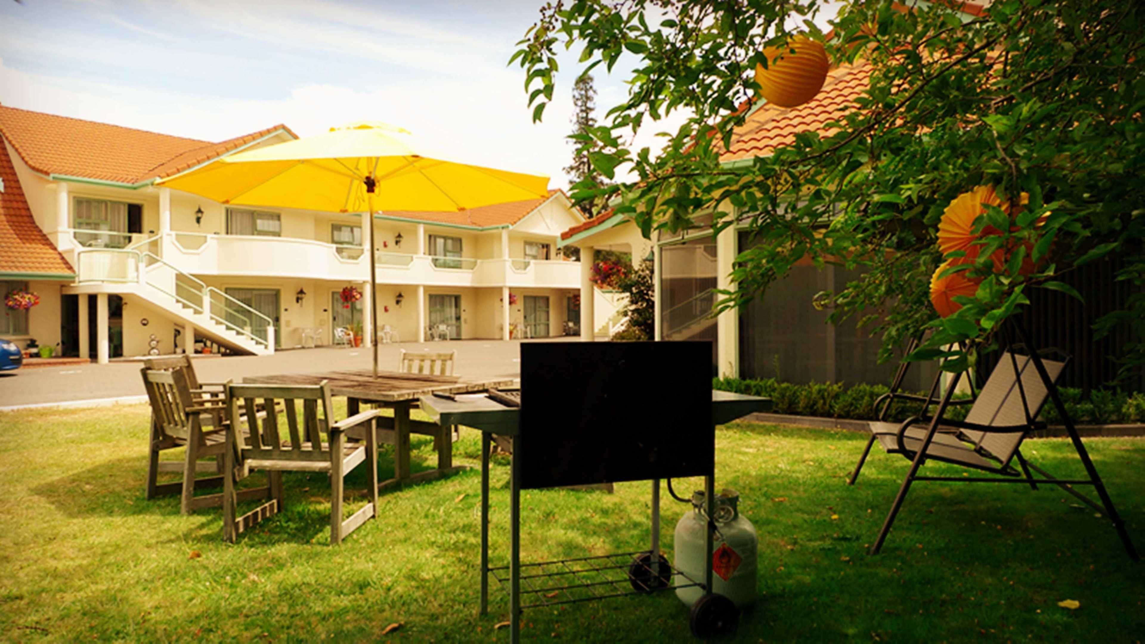 A hotel courtyard with outdoor seating, a yellow umbrella, and a gas cylinder.
