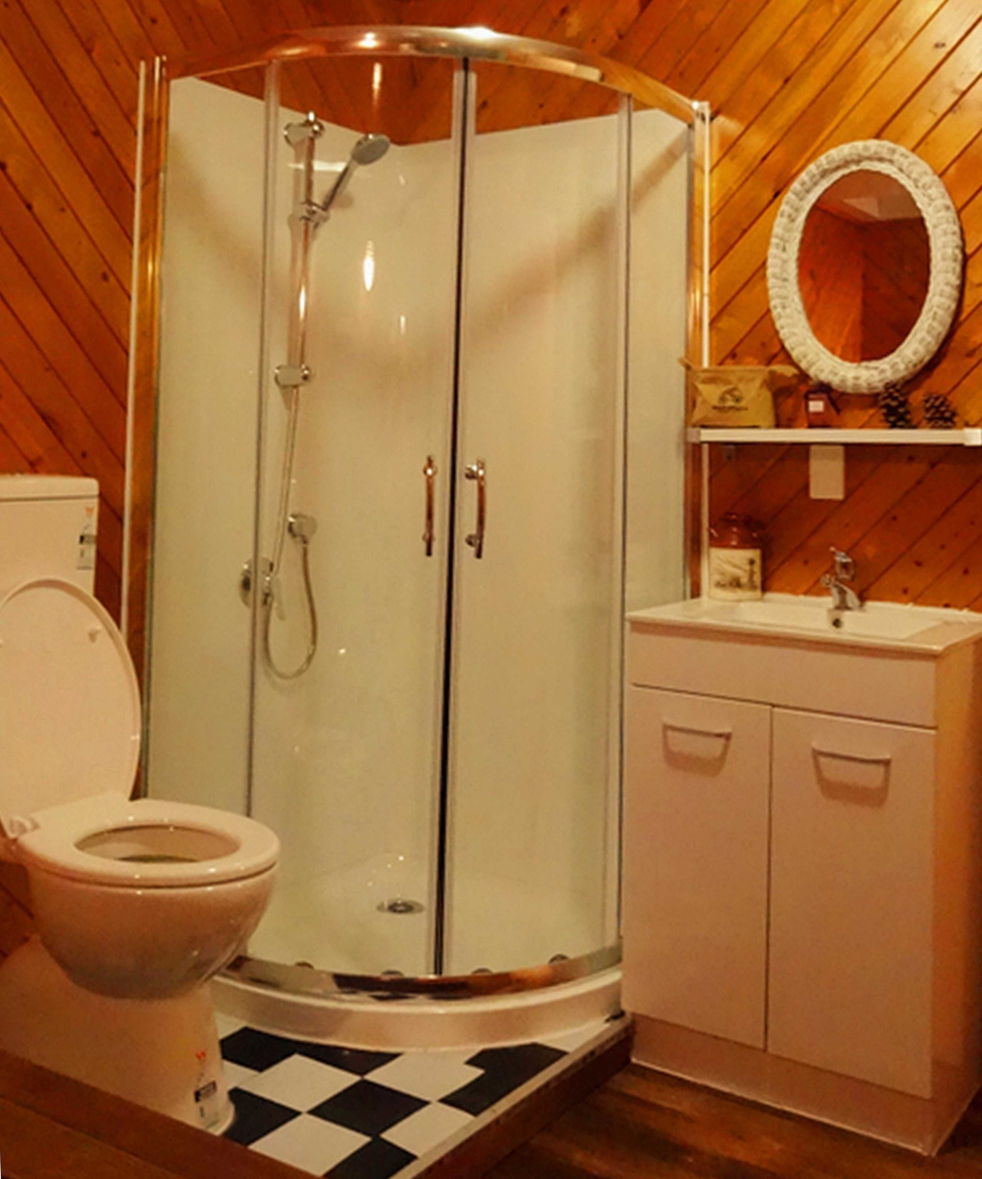 Un baño con ducha de vidrio, inodoro, lavabo y espejo.