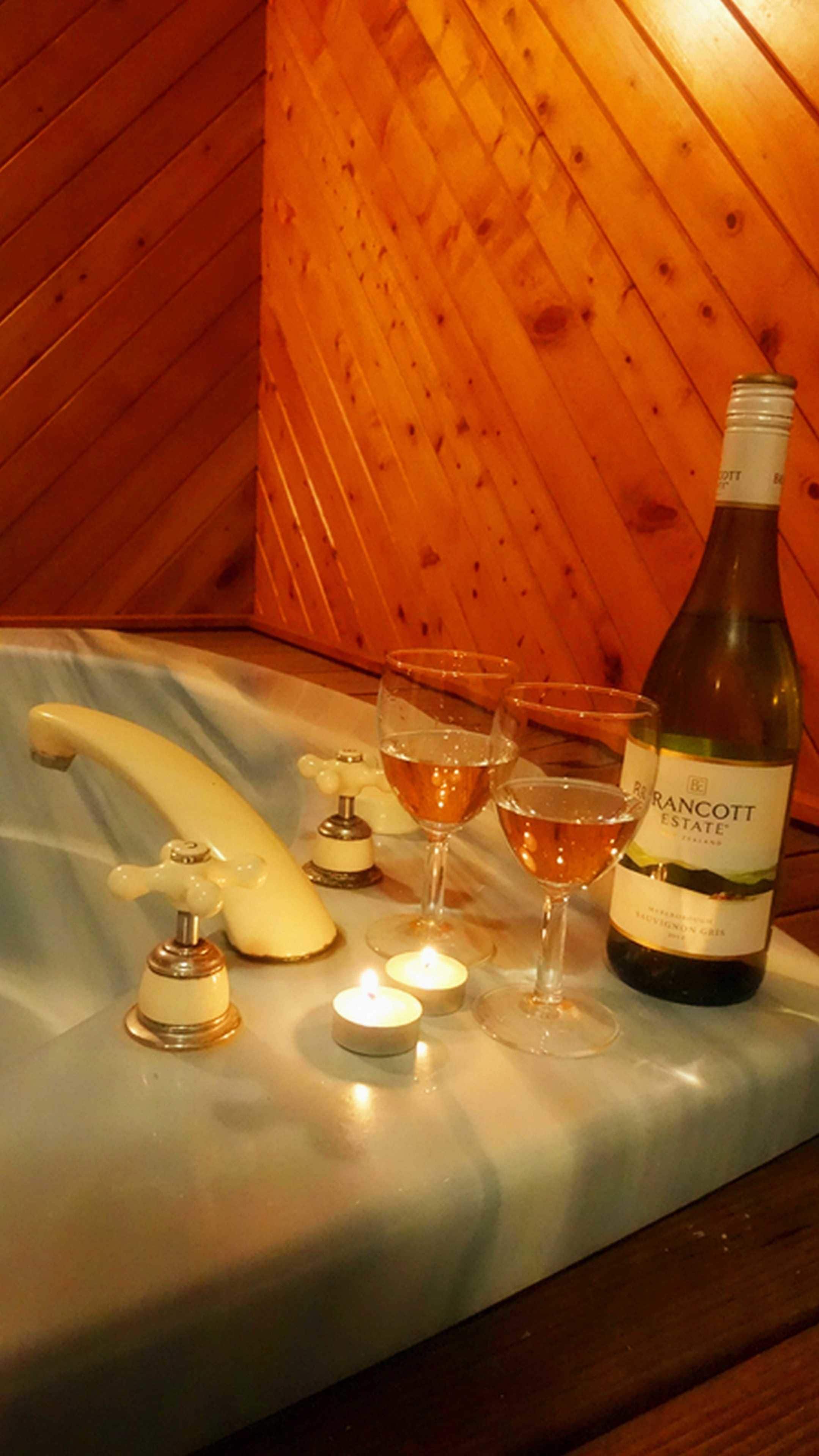 A bottle of wine, three glasses, a candle, and a wine opener on a marble surface.