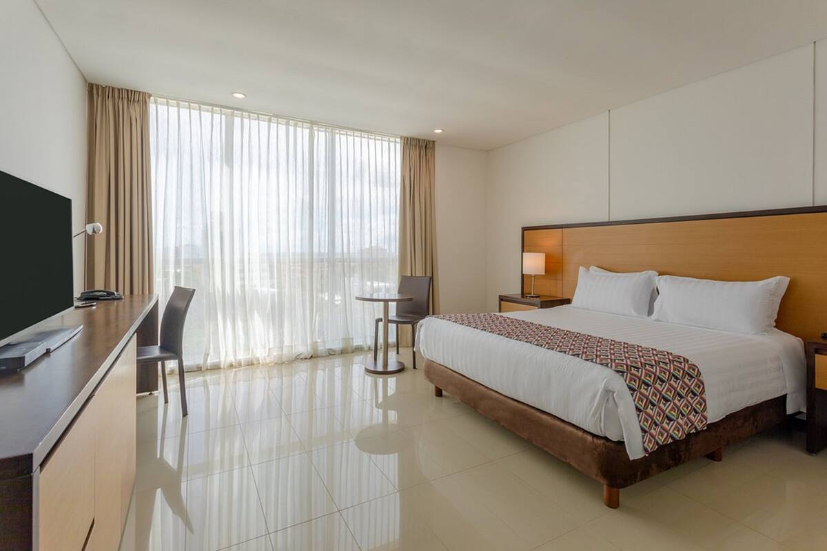 Een hotelkamer met een bed, bureau, stoel en een televisie.