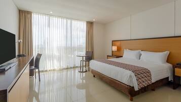 Habitación de hotel con cama, escritorio, silla y televisión.