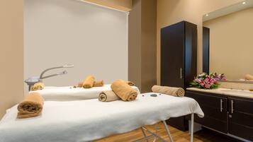 Relax in a serene spa room with two treatment tables, a large mirror, and a self-service area with a sink.