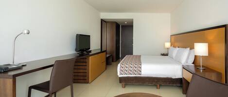 Ein Hotelzimmer mit Bett, Schreibtisch, Stuhl, Fernseher und einem kleinen Tisch.