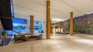 Un'ampia hall con una scalinata, un'area salotto e un muro in pietra.