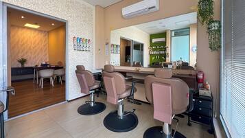 Un salón con cuatro sillas, un espejo y una barra con varios productos para el cabello.