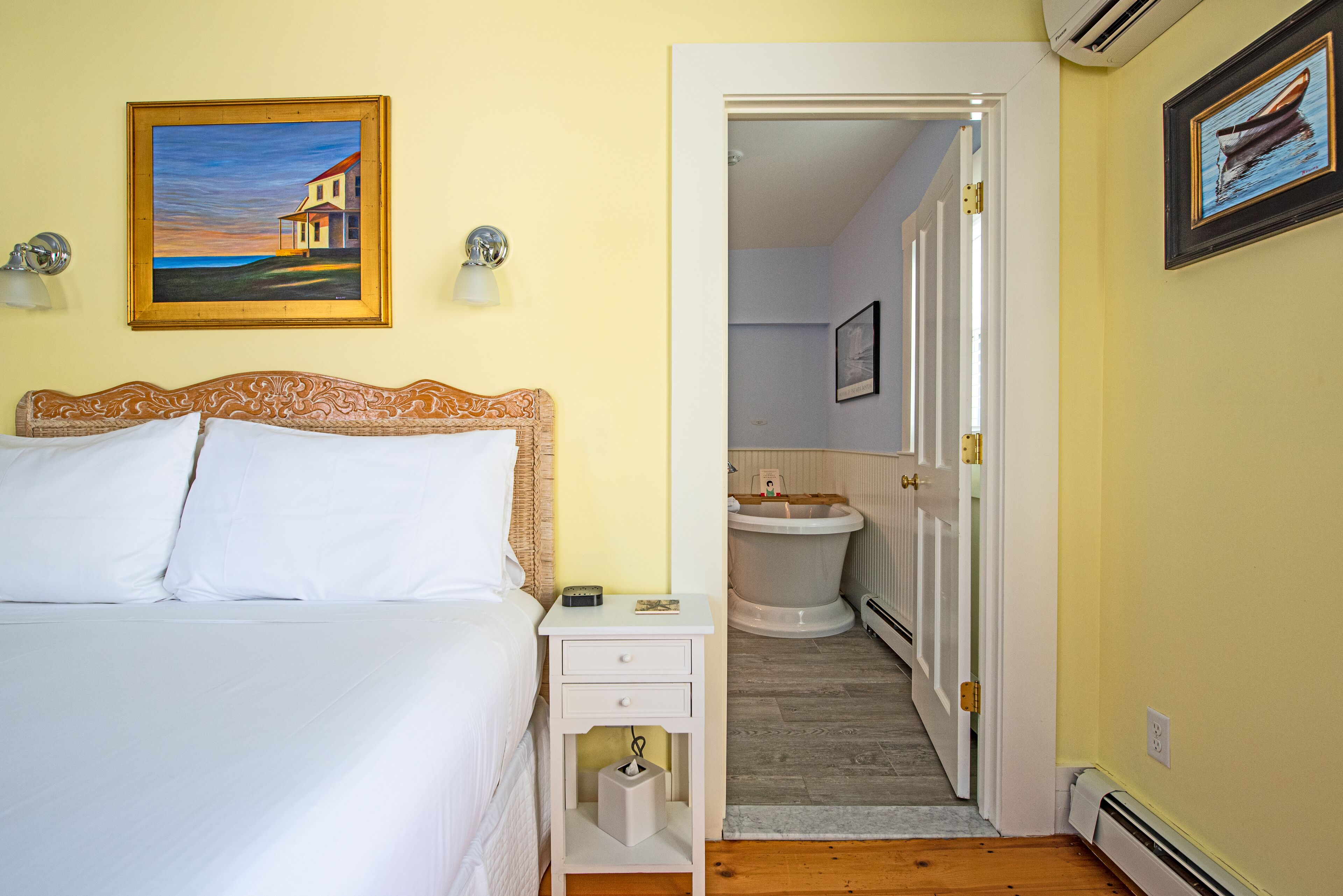 Een slaapkamer met een bed, nachtkastje en een schilderij aan de muur.