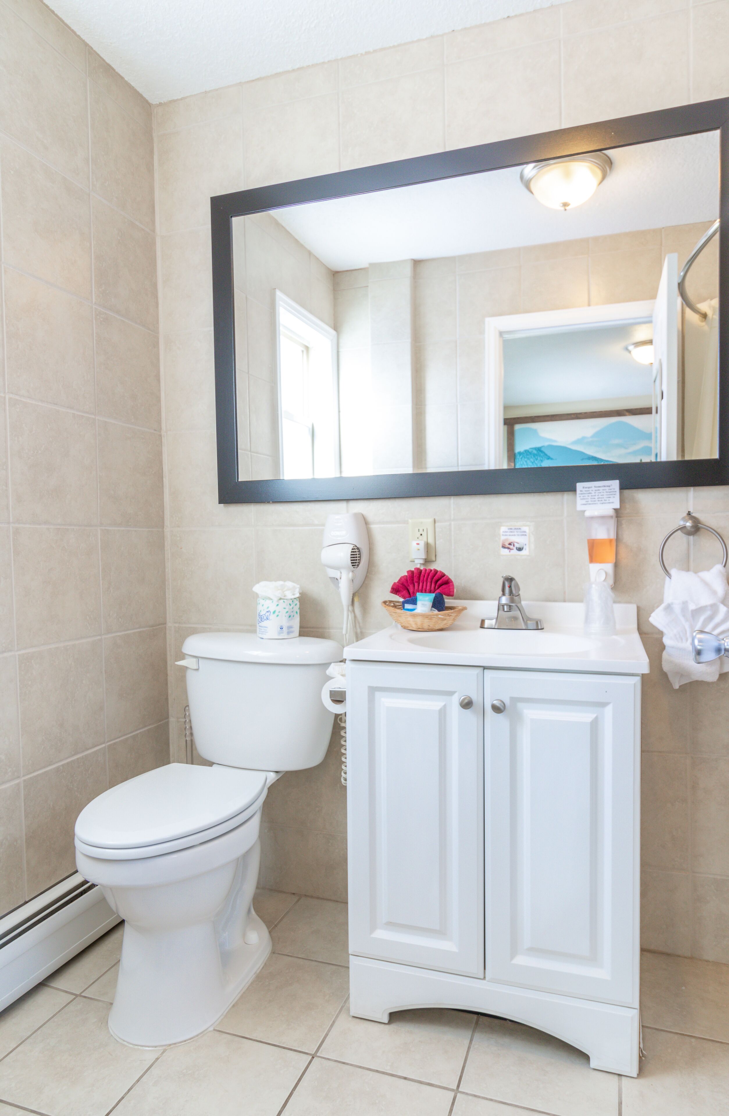 A bathroom with a toilet, a sink, a mirror, and a towel rack.