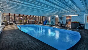 An indoor swimming pool with a glass ceiling, lounge chairs, and a sauna area. - Murphy's River Lodge (Estes Park)
