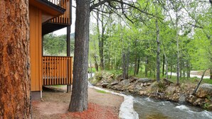 A wooden cabin with a deck overlooking a river. - Murphy's River Lodge (Estes Park)