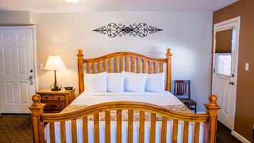 Een netjes opgemaakt bed met een houten hoofdbord, een bedlampje en een decoratief kunstwerk erboven.