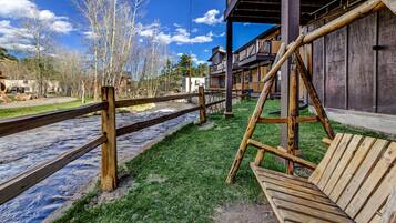 A wooden deck with a bench, a wooden fence, and a view of a river and buildings in the background.