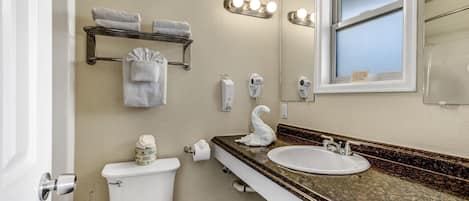 A bathroom with a toilet, sink, vanity, towel rack, and a window with blinds.