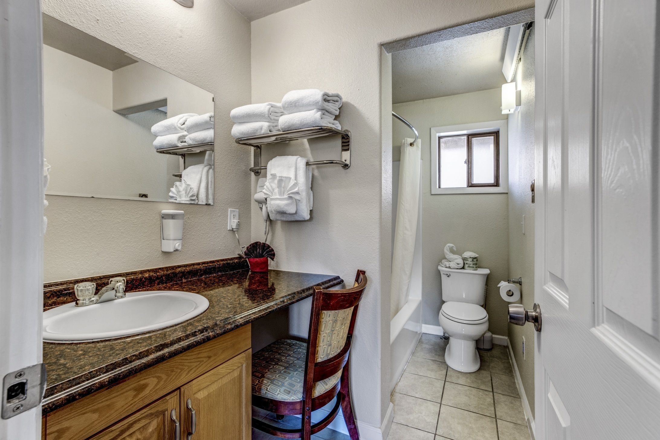A bathroom with a sink, mirror, towel rack, toilet, and shower area.