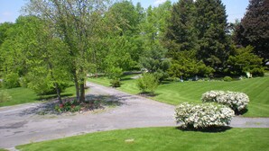 Une pelouse bien entretenue, une allée pavée et une variété d’arbres et d’arbustes.