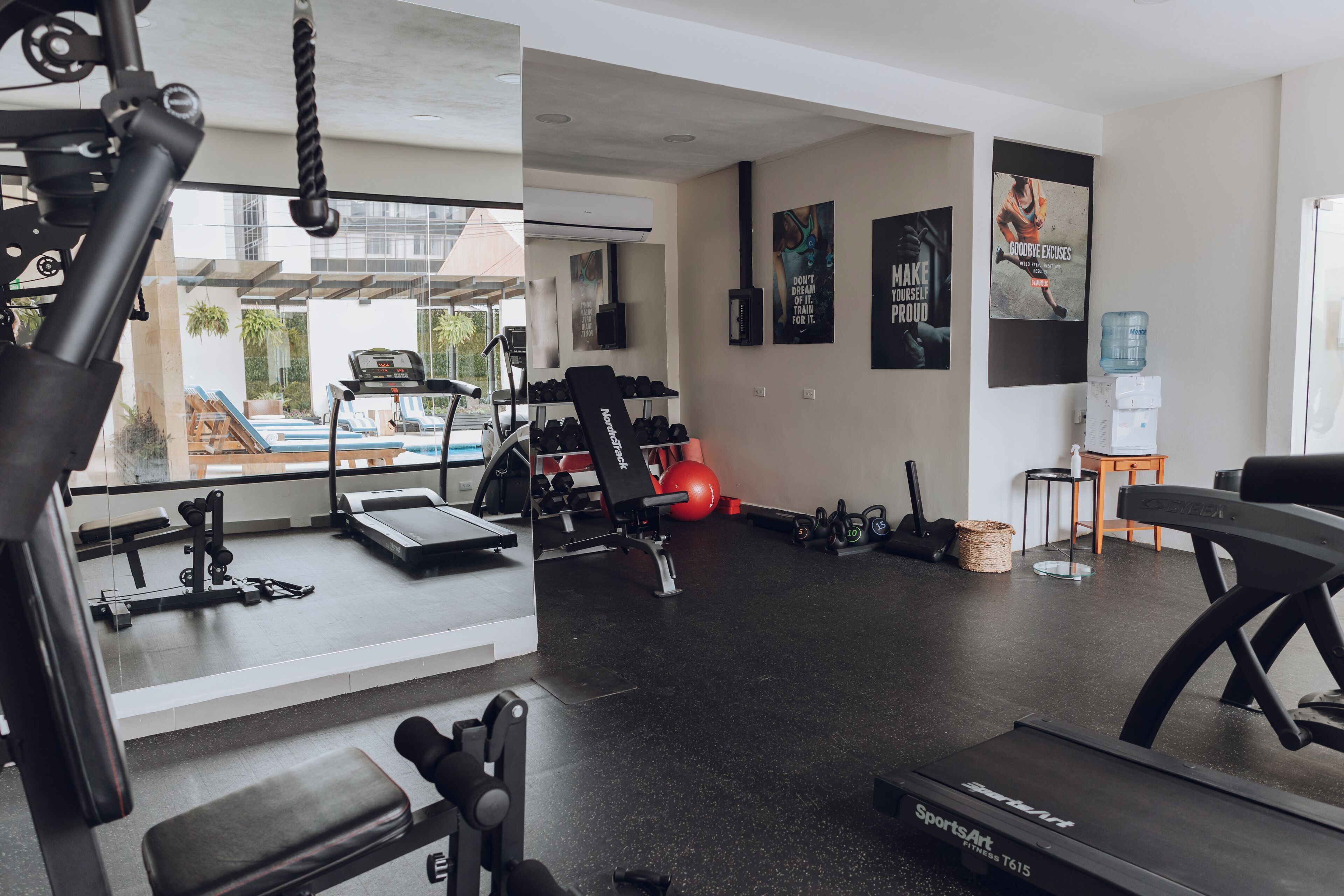 A gym with exercise equipment, a treadmill, and motivational posters on the wall.