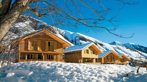 A wooden cabin with a balcony, surrounded by snow-covered mountains. - Résidence Odalys Les Chalets de l'Arvan II (Saint-Sorlin-d'Arves)