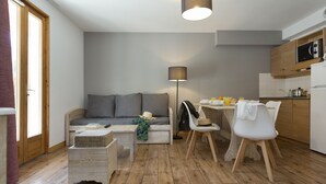 A compact living space with a sofa, dining table, chairs, and a lamp. - Résidence Odalys Les Chalets de l'Arvan II (Saint-Sorlin-d'Arves)