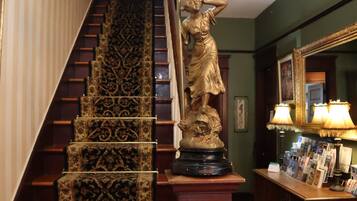 Eine prächtige Treppe mit aufwendig gestalteten Teppichstufen, einer Statue und einer Lampe.