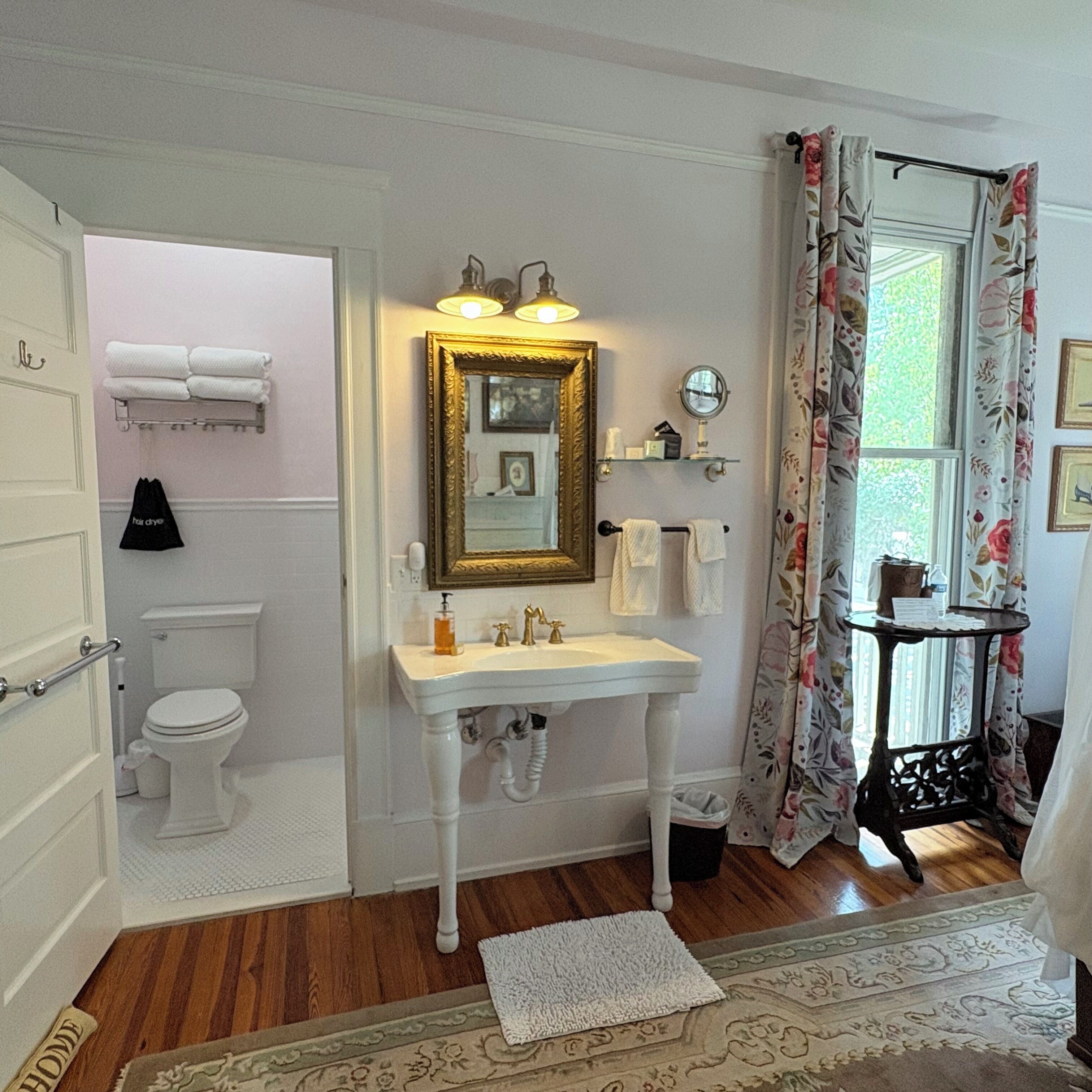 A bathroom with a white sink, gold-framed mirror, and a toilet.
