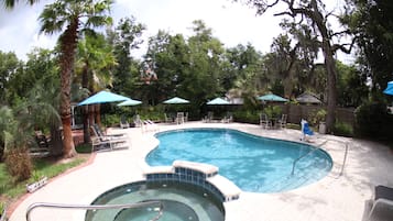 Una piscina con jacuzzi, rodeada de sillas de descanso y sombrillas.