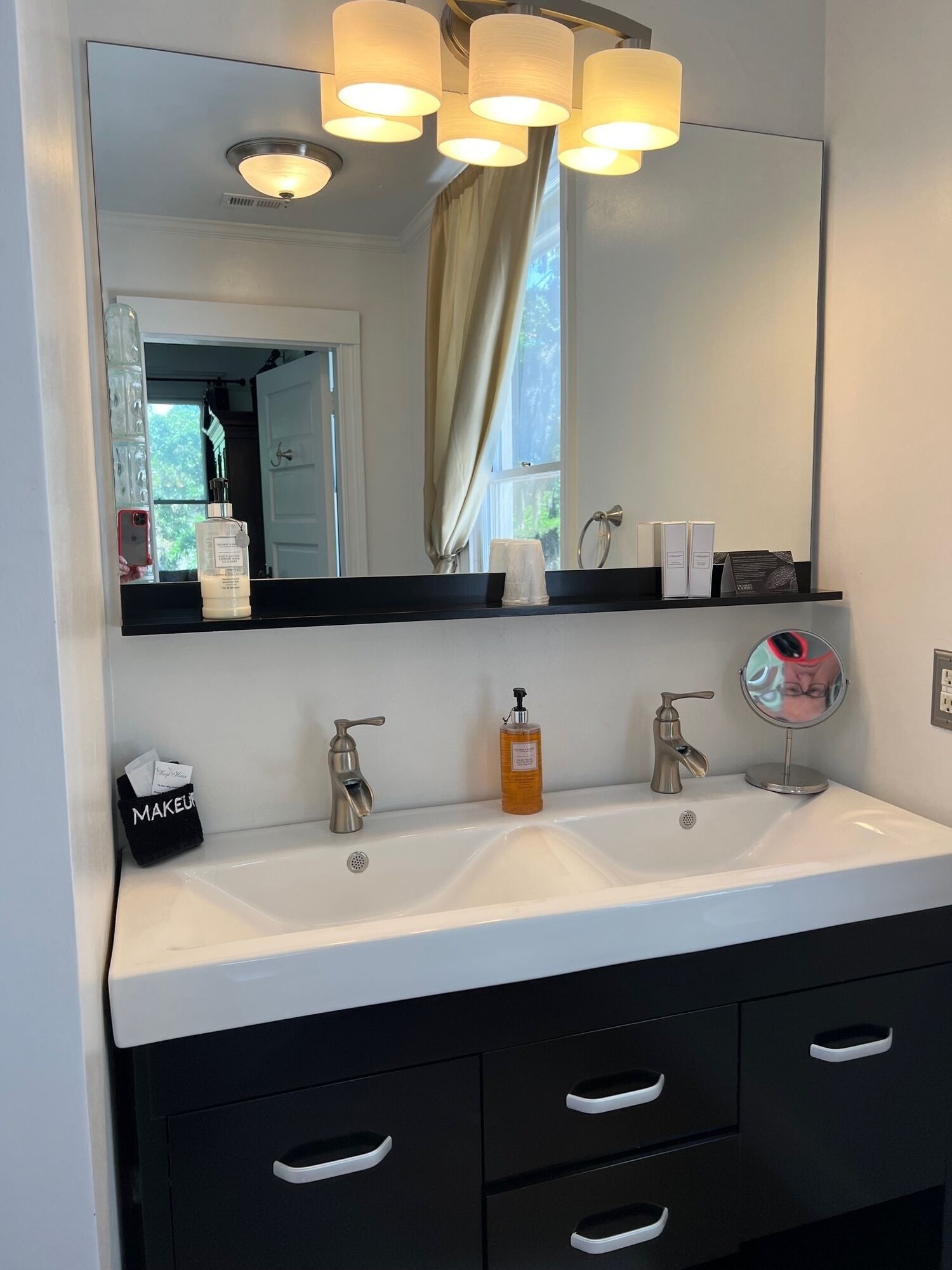 A bathroom with two sinks, a mirror, and a vanity with drawers.