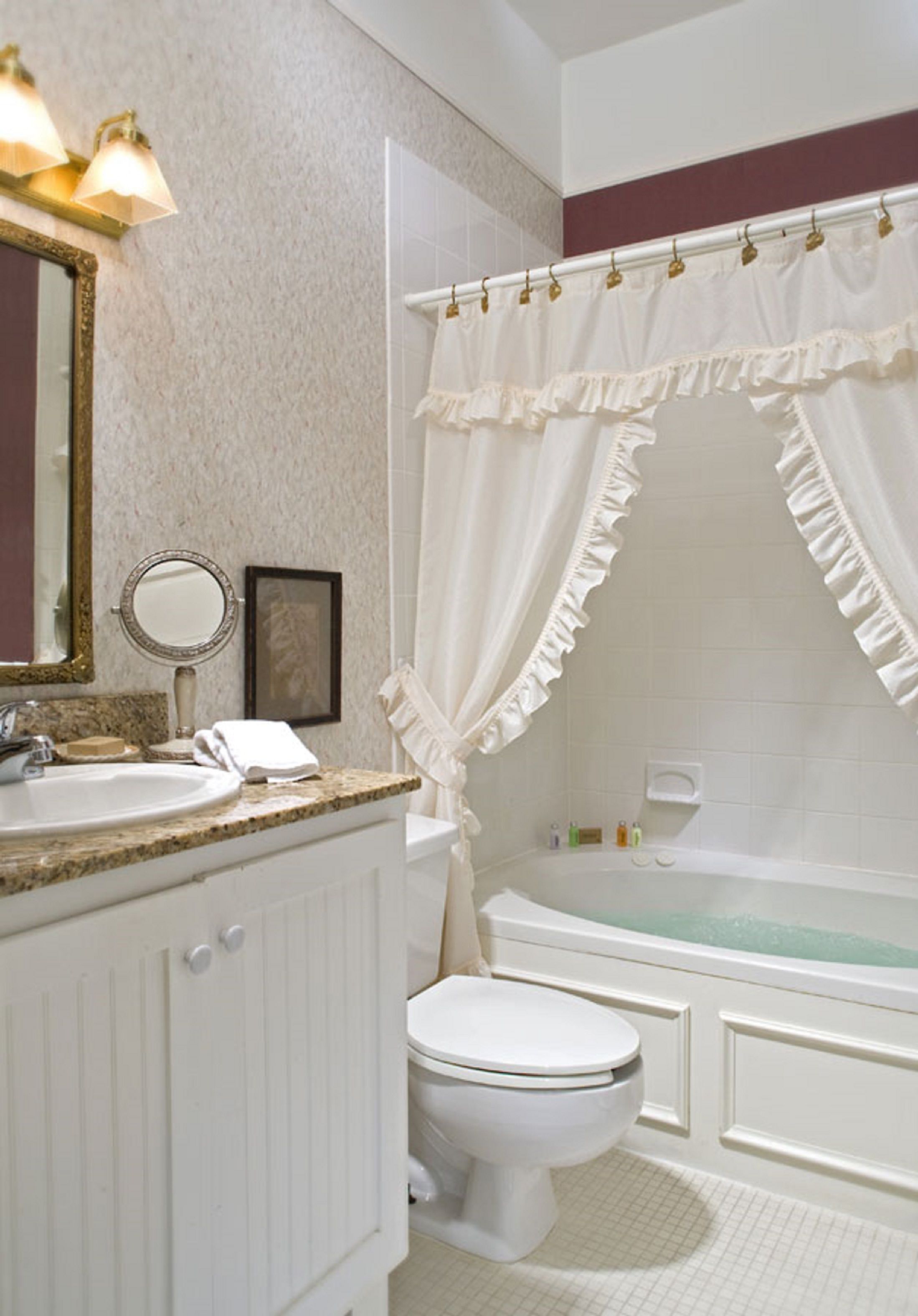 Een badkamer met een wit wastafelmeubel, een wastafel, toilet en een bad.